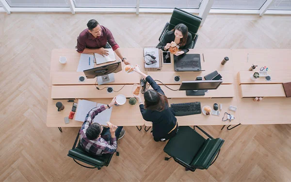 An above view of a group of four people who are seated around a conference table.