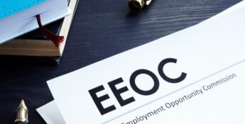 An EEOC document lies on the desk alongside EEO-1 data, accompanied by a pen and notebooks, reflecting Equal Employment Opportunity Commission material.