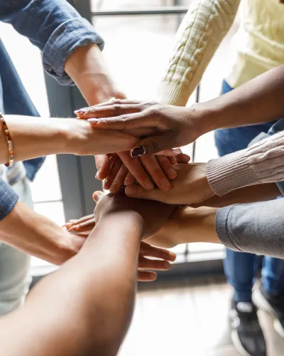 3 sets of hands stacked on top of each other to highlight teamwork and community