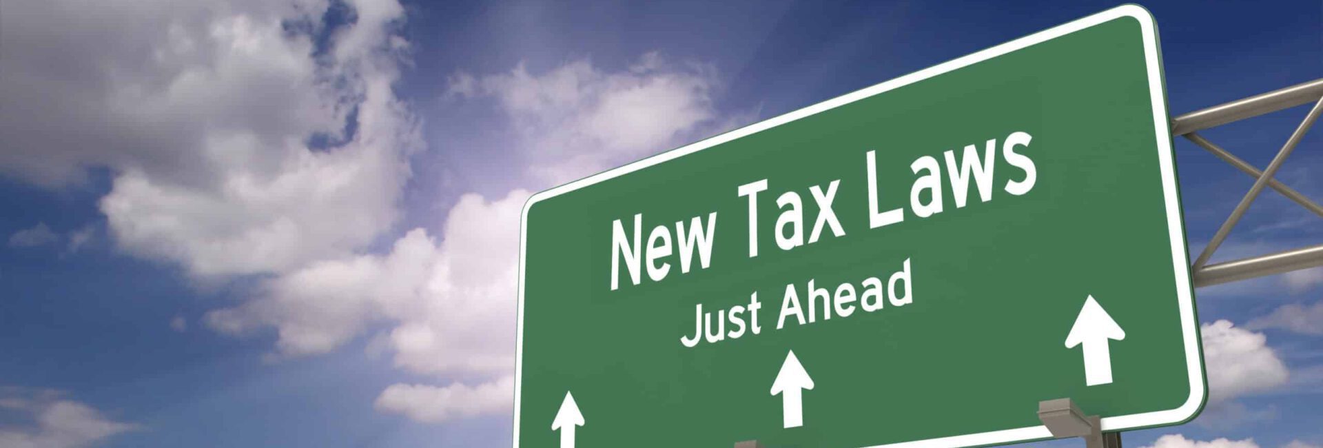 Green highway sign reads "Newly Proposed 2023 Tax Deductions Just Ahead" with arrows pointing forward, set against a partly cloudy sky.