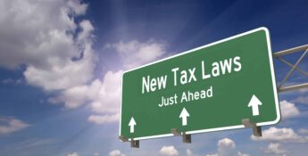 Green highway sign reads "Newly Proposed 2023 Tax Deductions Just Ahead" with arrows pointing forward, set against a partly cloudy sky.