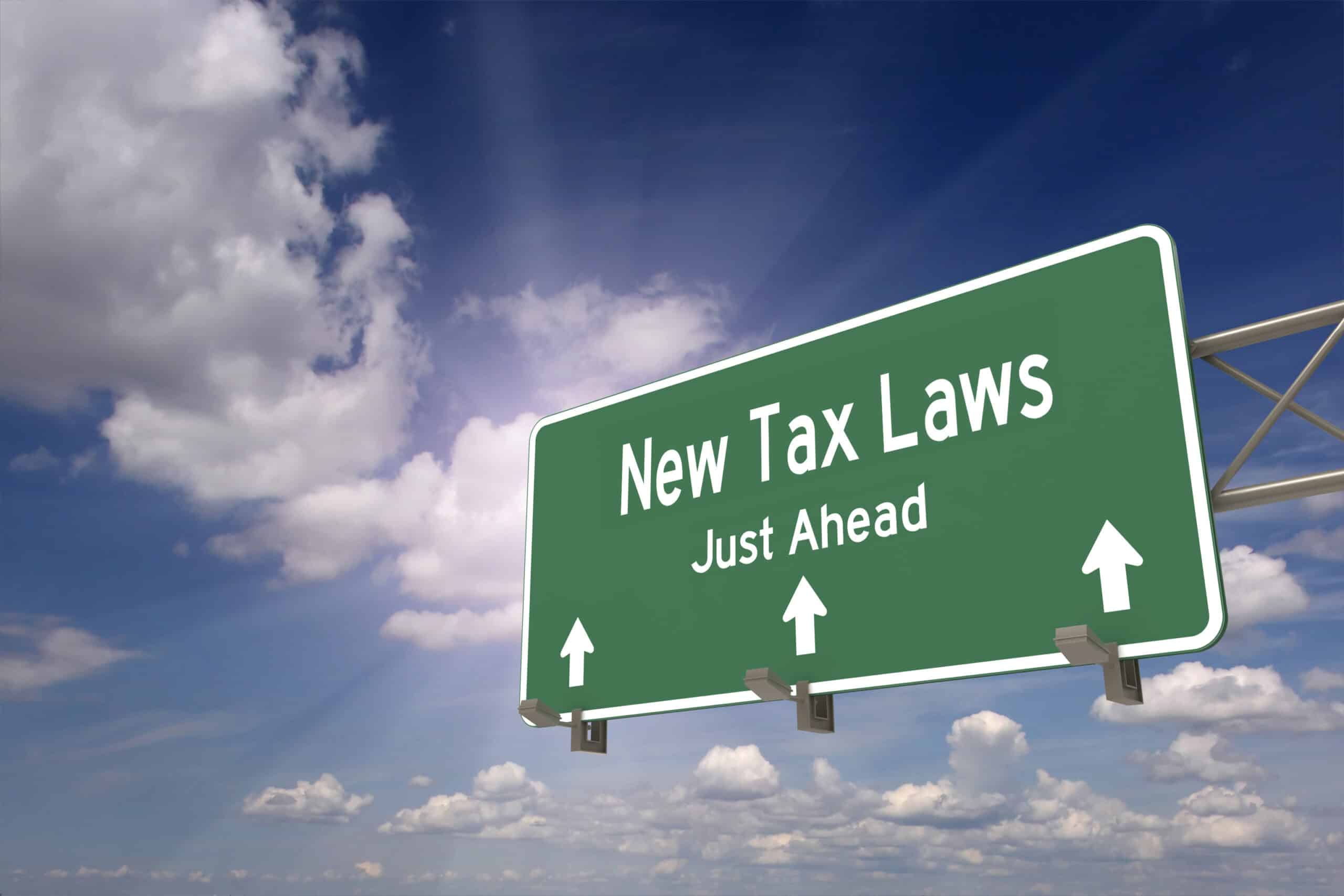 Green highway sign reads "Newly Proposed 2023 Tax Deductions Just Ahead" with arrows pointing forward, set against a partly cloudy sky.