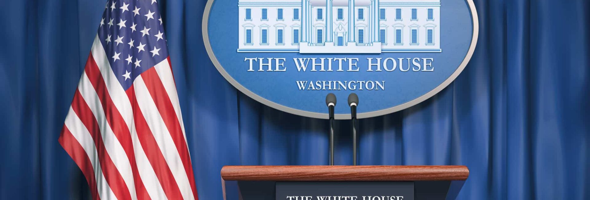 Press podium at the White House with microphones, a sign displaying "The White House, Washington," and a U.S. flag in the background against a blue curtain.