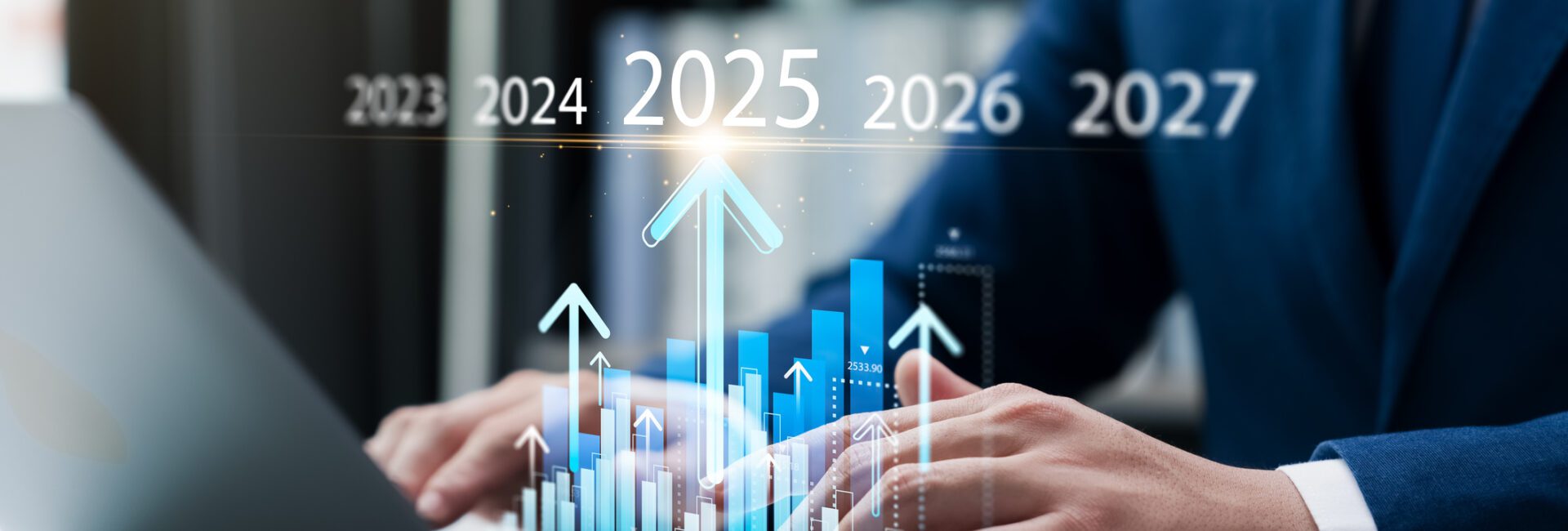 Person using a laptop with a graph overlay, indicating rising trends from 2023 to 2027.
