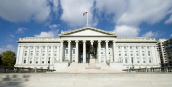 Front view of a large neoclassical building with tall columns, exuding the gravitas of governance, featuring a statue and an American flag flying above—a symbol that echoes the principles of the Corporate Transparency Act.