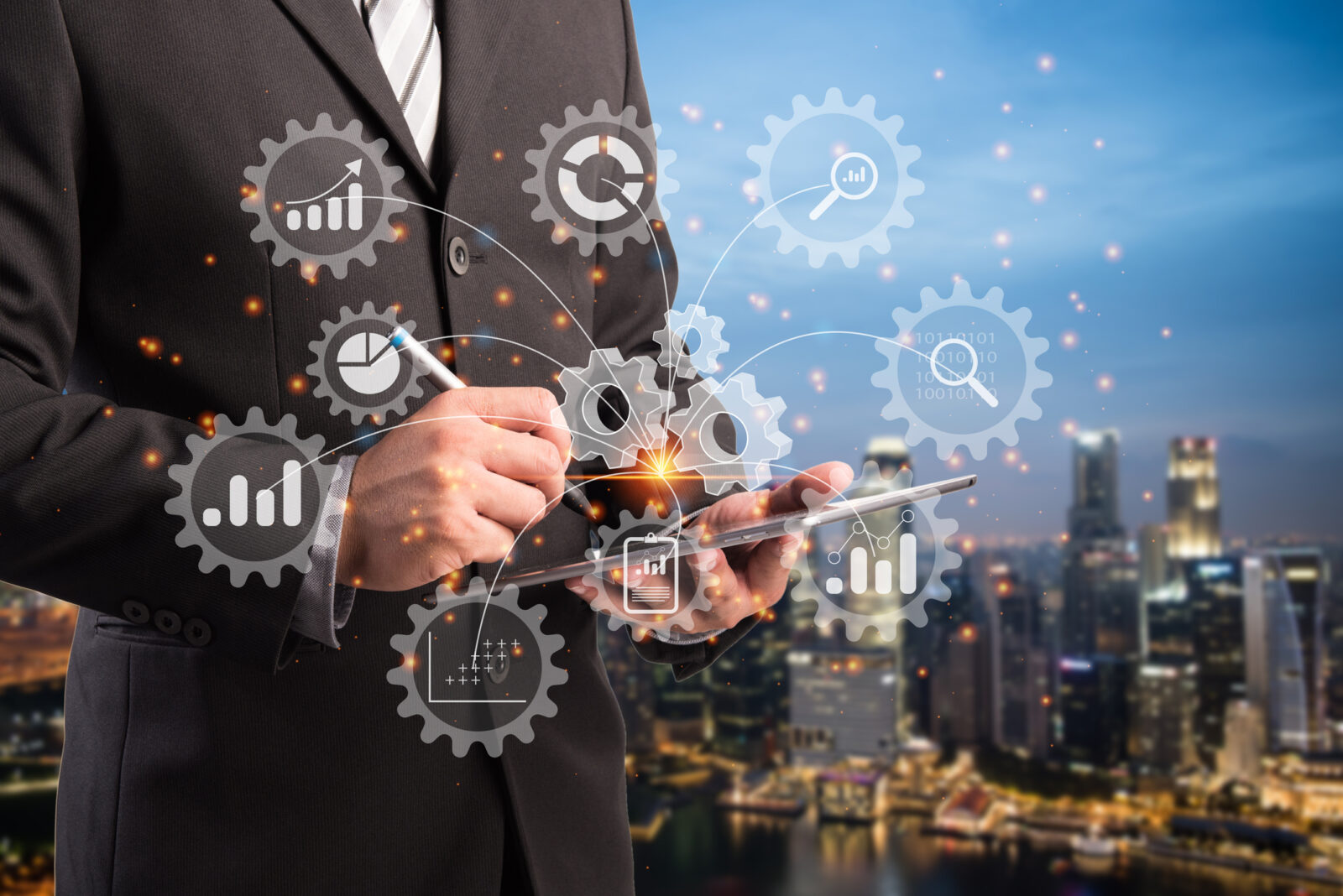 Businessperson using a digital tablet overlaid with holographic gears and charts, symbolizing technology and data analytics, with a cityscape in the background.