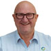 A bald man wearing glasses and a light blue collared shirt, smiling at the camera against a white background.