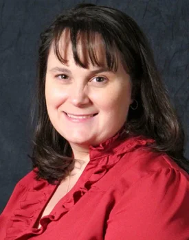 Roxie with shoulder-length dark hair wearing a red blouse, smiling confidently against a dark background, embodying the professionalism and expertise of transactional advisory.