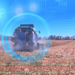 A combine harvester works in a field under a blue sky, with digital graphics and data overlays representing agricultural technology and precision farming.