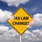Yellow road sign with the words "TAX LAW CHANGES" against a partly cloudy blue sky.