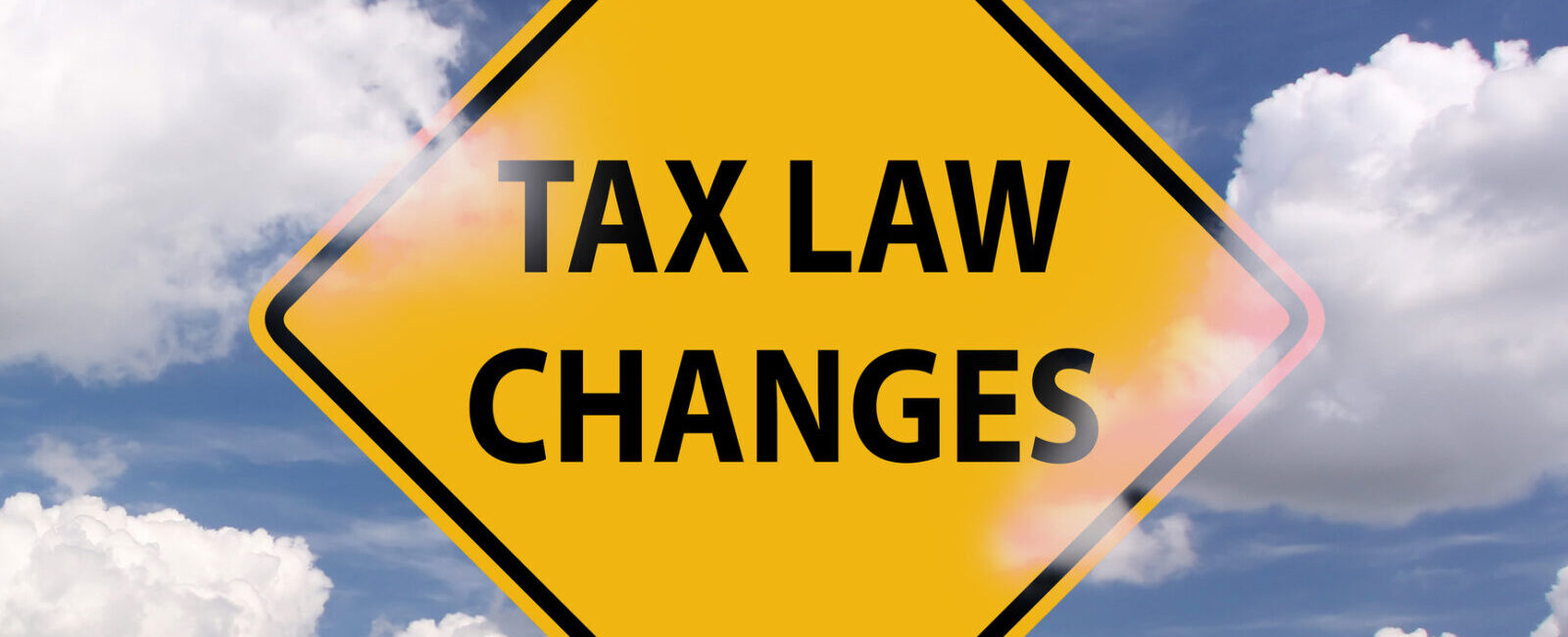 Yellow road sign with the words "TAX LAW CHANGES" against a partly cloudy blue sky.