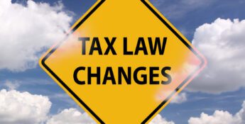 Yellow road sign with the words "TAX LAW CHANGES" against a partly cloudy blue sky.
