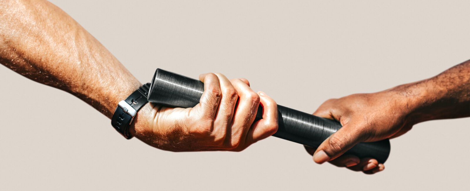 Two hands passing a black baton to each other, symbolizing a relay race or transfer of responsibility, against a plain background.