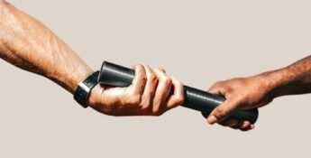 Two hands passing a black baton to each other, symbolizing a relay race or transfer of responsibility, against a plain background.