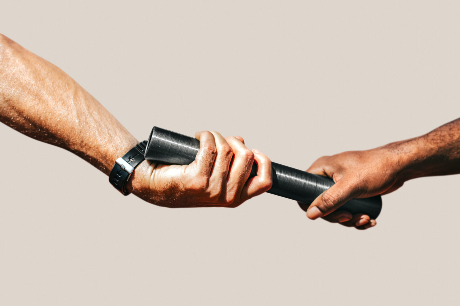 Two hands passing a black baton to each other, symbolizing a relay race or transfer of responsibility, against a plain background.