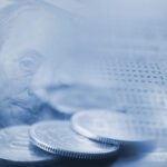 Close-up of a pen, coins, and a dollar bill overlaid with a blurred financial statement, symbolizing money management or financial planning.
