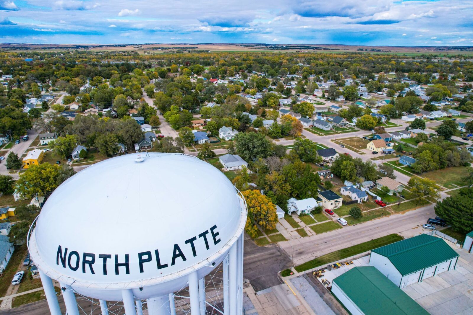 Aerial view of a white water tower labeled "North Platte" in North Platte NE, overlooking a suburban neighborhood with trees and houses.