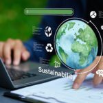 Person uses a laptop with sustainability icons, a globe, and charts overlayed, representing environmental data and eco-friendly practices.