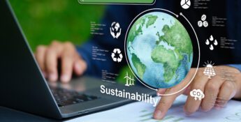 Person uses a laptop with sustainability icons, a globe, and charts overlayed, representing environmental data and eco-friendly practices.