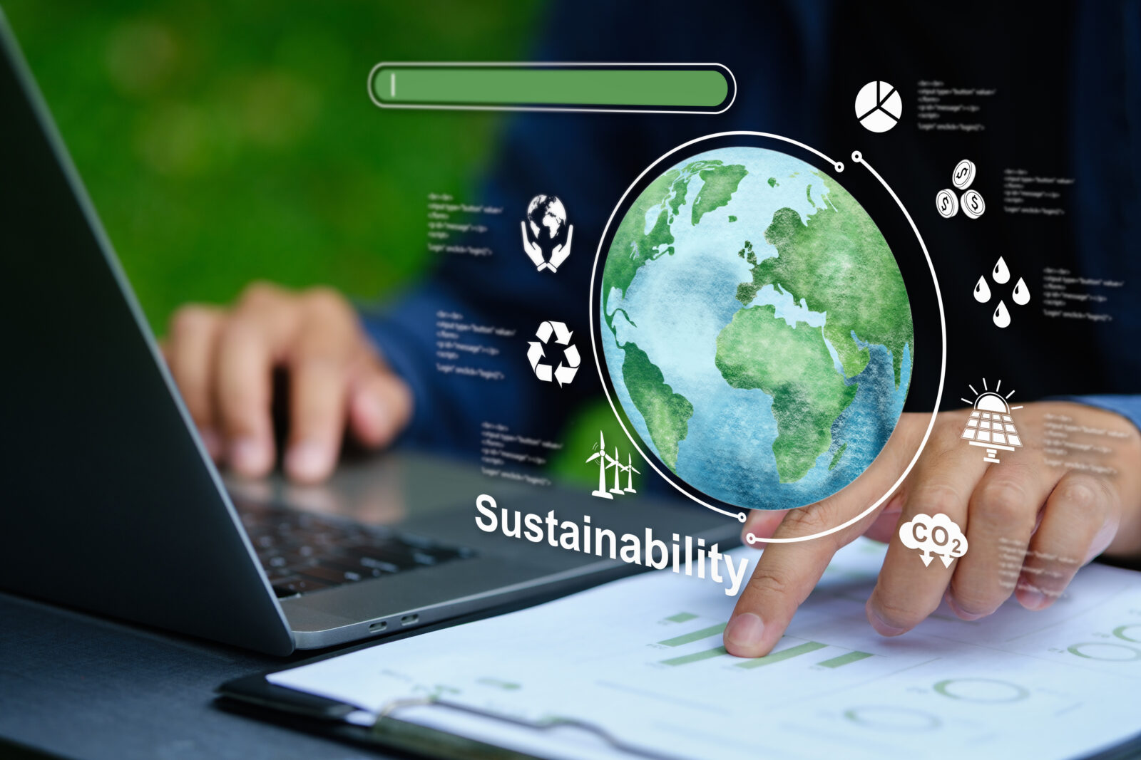 Person uses a laptop with sustainability icons, a globe, and charts overlayed, representing environmental data and eco-friendly practices.