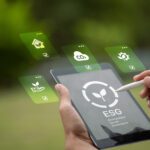 A person uses a stylus on a tablet displaying an ESG logo, with floating icons representing environmental, social, and governance concepts alongside sustainability data.