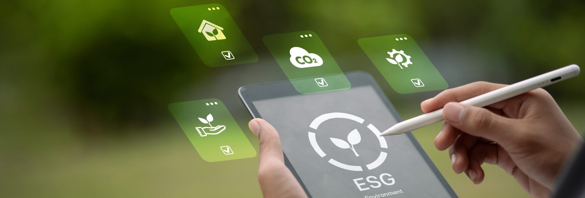 A person uses a stylus on a tablet displaying an ESG logo, with floating icons representing environmental, social, and governance concepts alongside sustainability data.