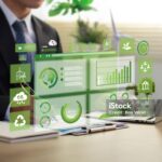 A person in business attire sits at a desk with a laptop, while digital sustainability and environmental graphics overlay the image.