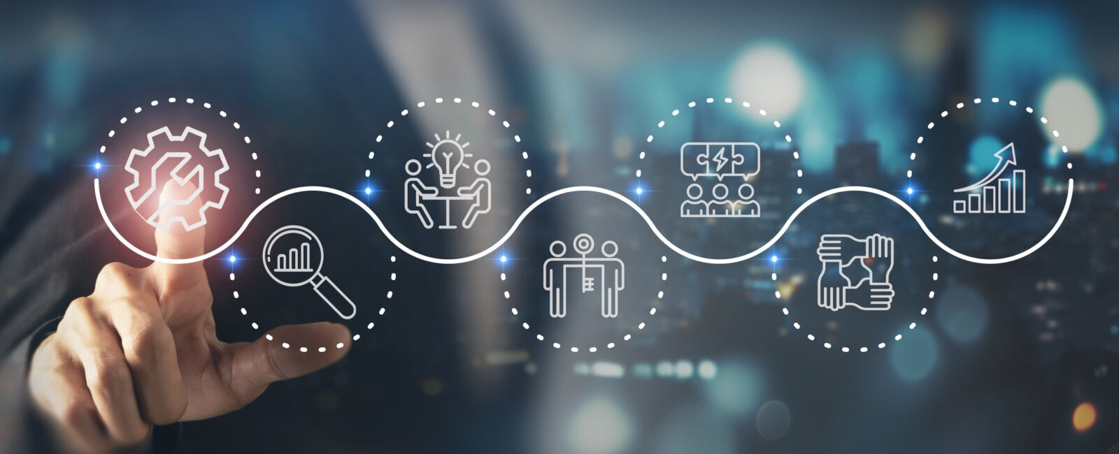 A person points at a digital display showing icons representing workflow steps: process, search, idea, team, analytics, and collaboration, connected by a wavy line.