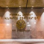 Lobby wall with "Federal Deposit Insurance Corporation" and seal, along with the address "550 17th Street" inscribed in gold lettering, highlights recent updates as the FDIC Signage Deadline Extended to 2027.