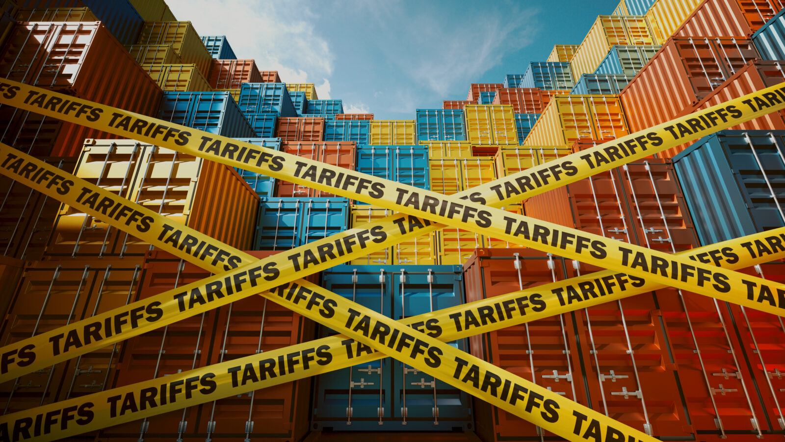 Stacks of colorful shipping containers are blocked by yellow tape labeled “TARIFFS,” symbolizing trade barriers. Blue sky and scattered clouds are visible above the containers.