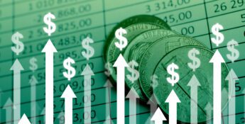 Coins on top of a financial spreadsheet with upward-pointing arrows and dollar signs, symbolizing financial growth or profit increase.