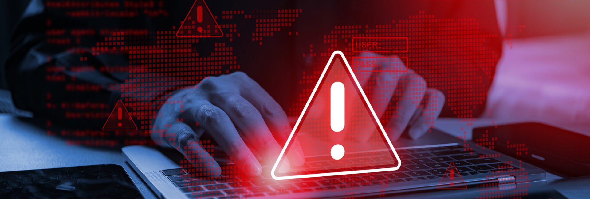 Hands typing on a laptop with a digital overlay of red warning icons and computer code.