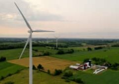 Aerial view of Wind turbines, windmill, farm, agricultural fields at sunrise sunset. Rural landscape. Renewable green energy concept, dawn dusk sky